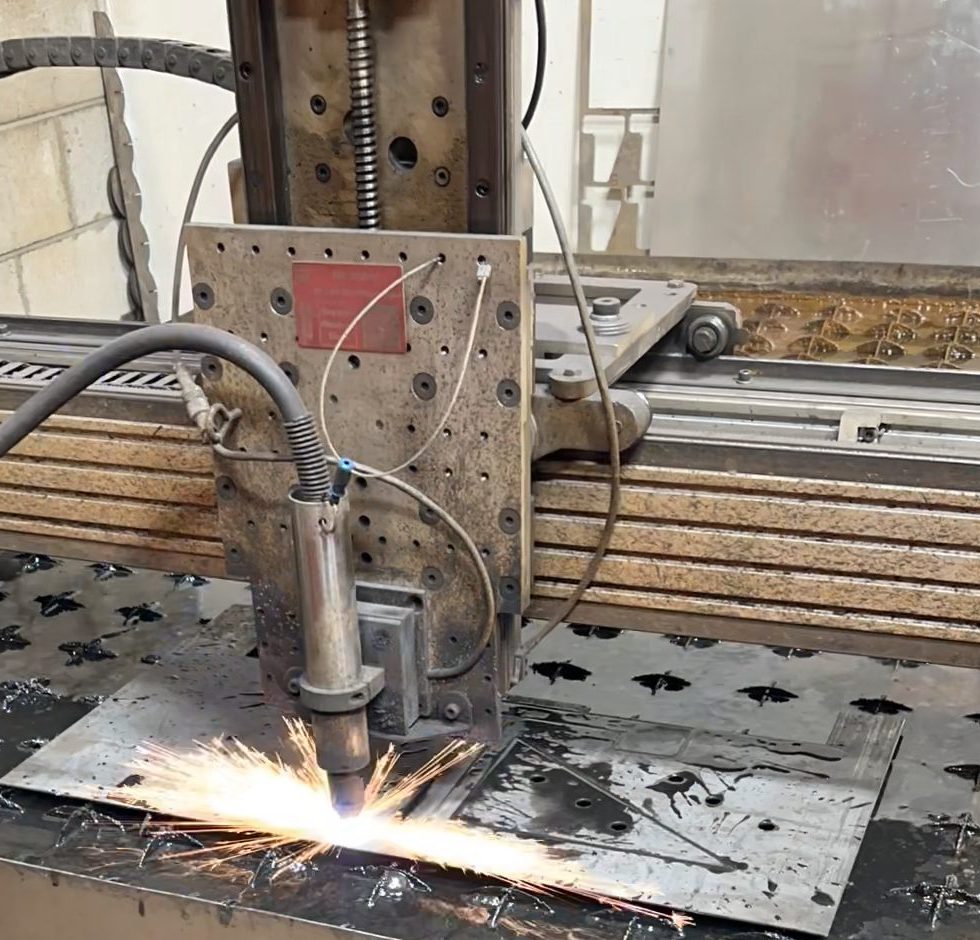 CNC plasma cutter throwing sparks as it cuts a steel plate