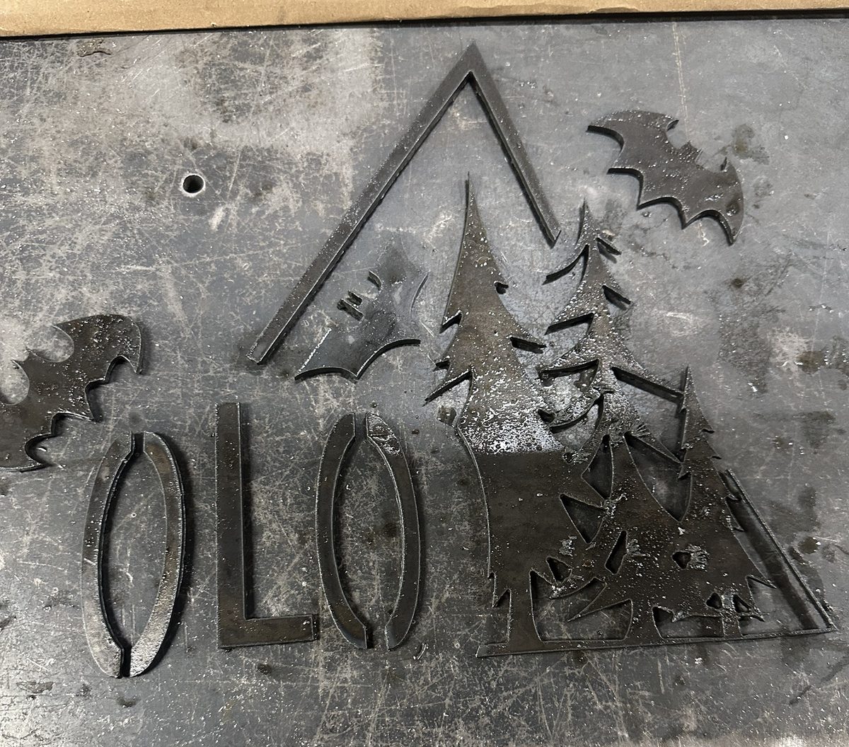 Plasma-cut steel sign with lettering, pine trees, a mountain outline and bats